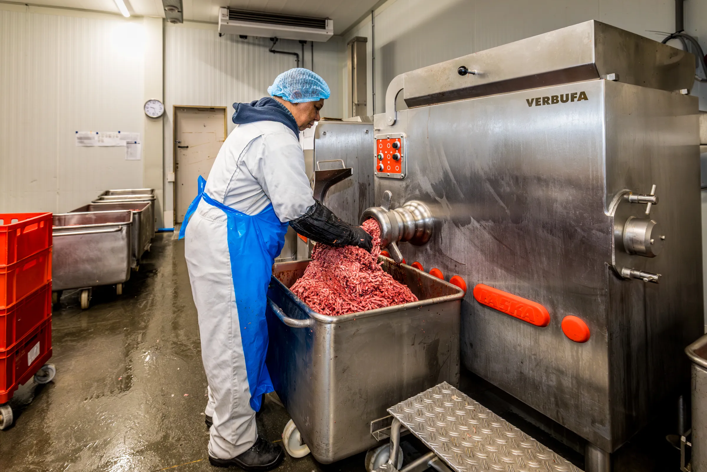 Medewerker verwerkt vers vlees in de vleesmolen