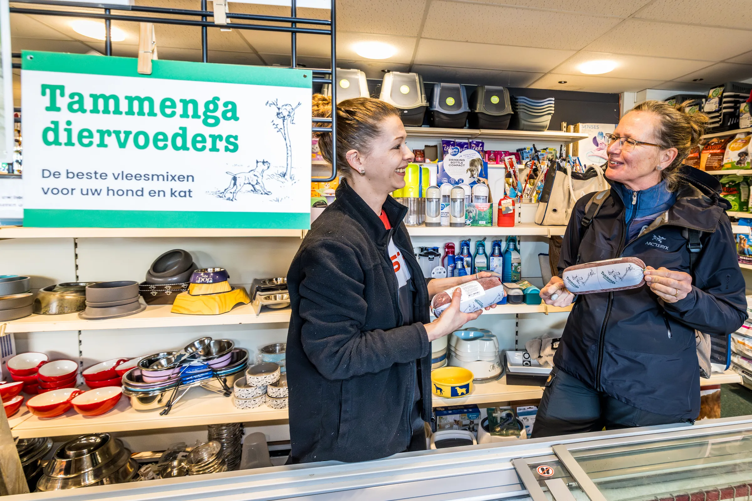 Medewerker van een Tammenga-verkooppunt geeft een product aan een klant
